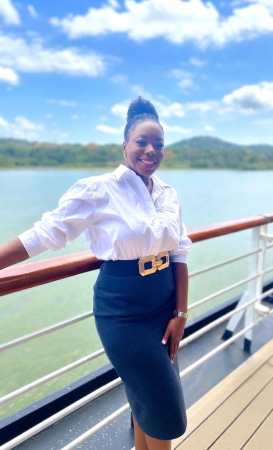 Hayley Molefe in uniform on a cruise ship deck beside a coastline